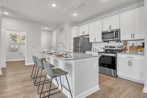 A kitchen with a white island and bar stools.